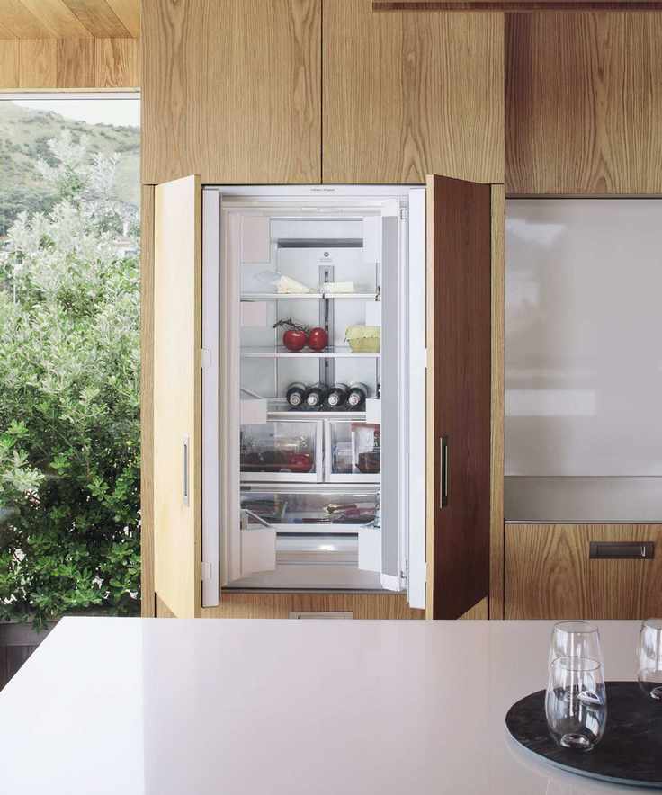 An open double door fridge built into a wooden custom cabinet