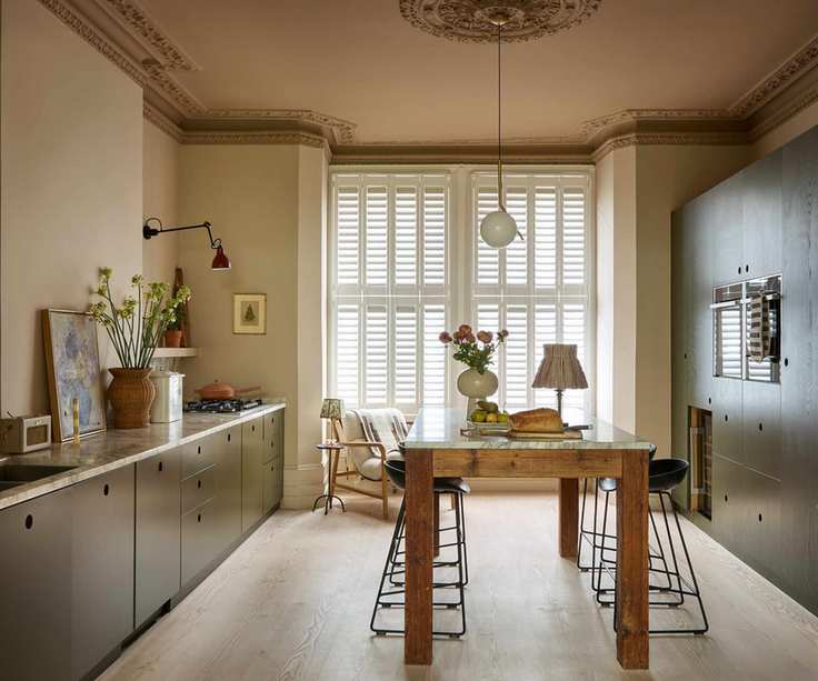 A galley kitchen with green cabinets and a freestanding wooden kitchen island