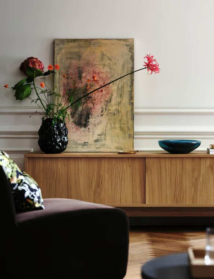Warm neutral living room with wooden sideboard and velvet chair