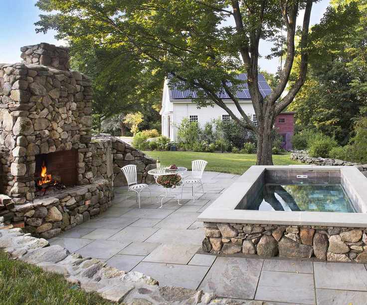 large plunge pool hot tub on a backyard patio with an outdoor fireplace