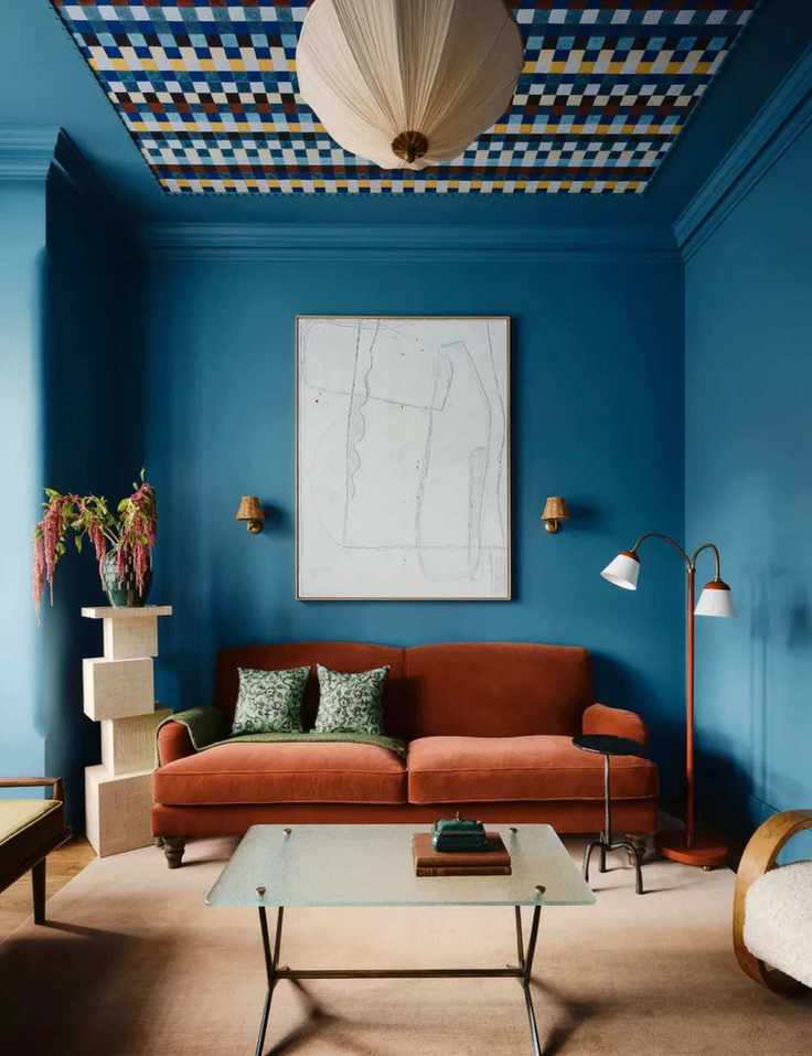 vibrant blue color drenched living room with a patterned accent ceiling and a deep velvet rust couch