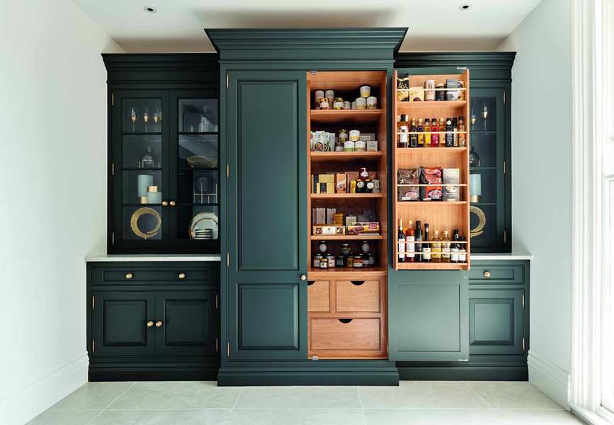 Floor to ceiling kitchen cabinetry in dark blue with larder shelving and glass fronted storage