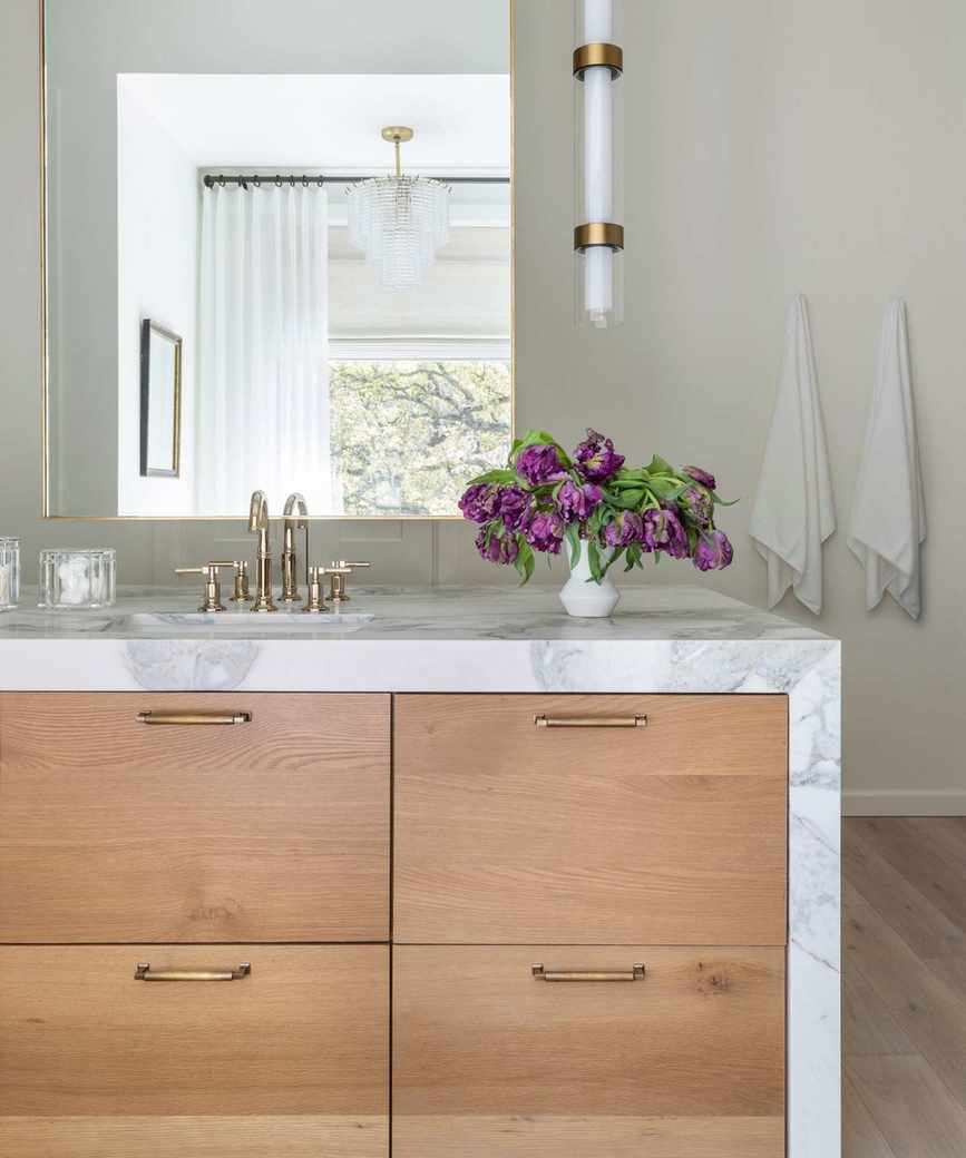 A wood and marble bathroom with a vanity island at the center