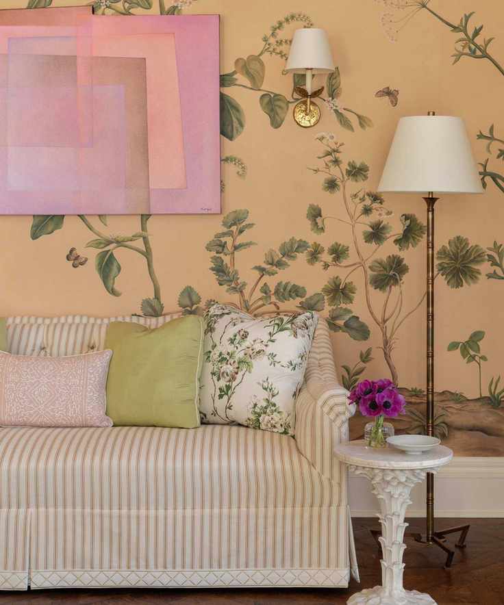 A living space adorned with peach botanical wallpaper, a pink striped sofa, and green accents.