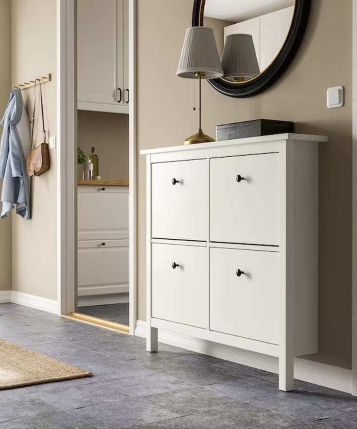 A white four section shoe storage cabinet against an entryway wall