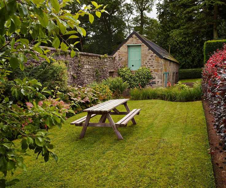 Flower and plant beds. Lawn, table and benches.