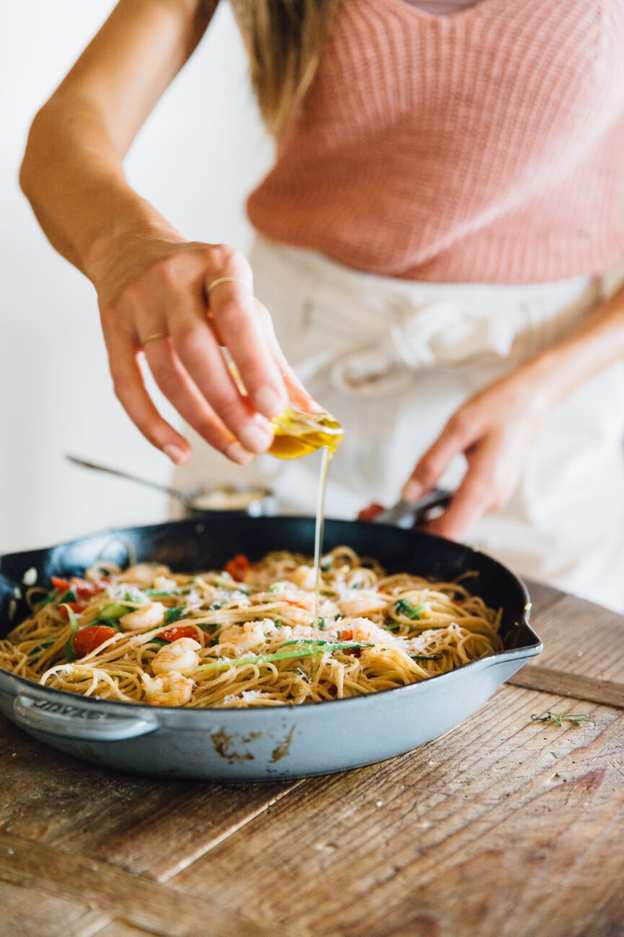drizzling olive oil on garlic and shrimp spaghetti