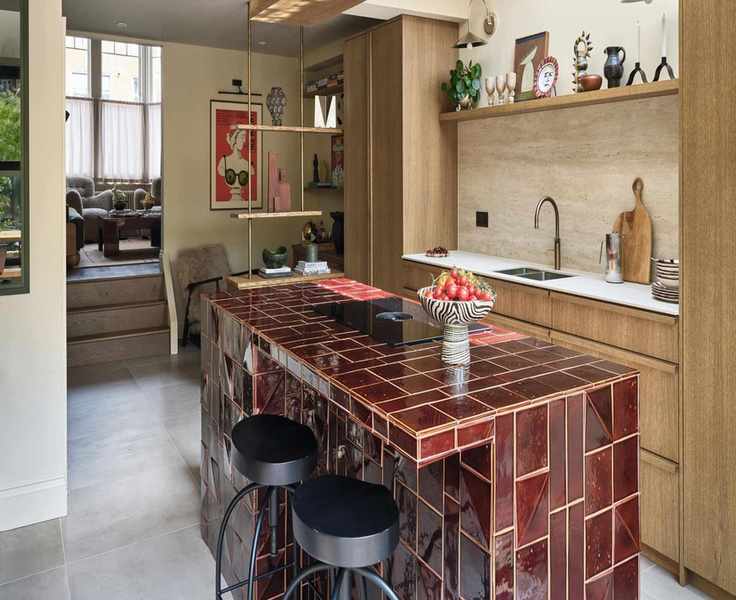 a wooden galley kitchen with a burgundy tiled kitchen island with black stools