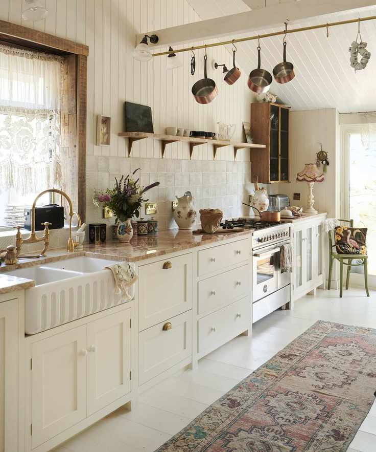 A white kitchen with off-white scandinavian cabinets, orange marble countertop and shiplap walls