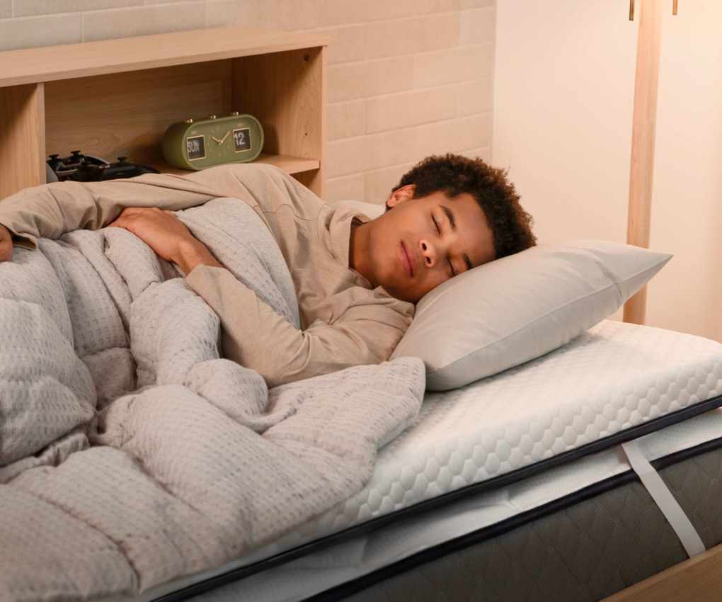 Teenager asleep on a bed showing mattress topper