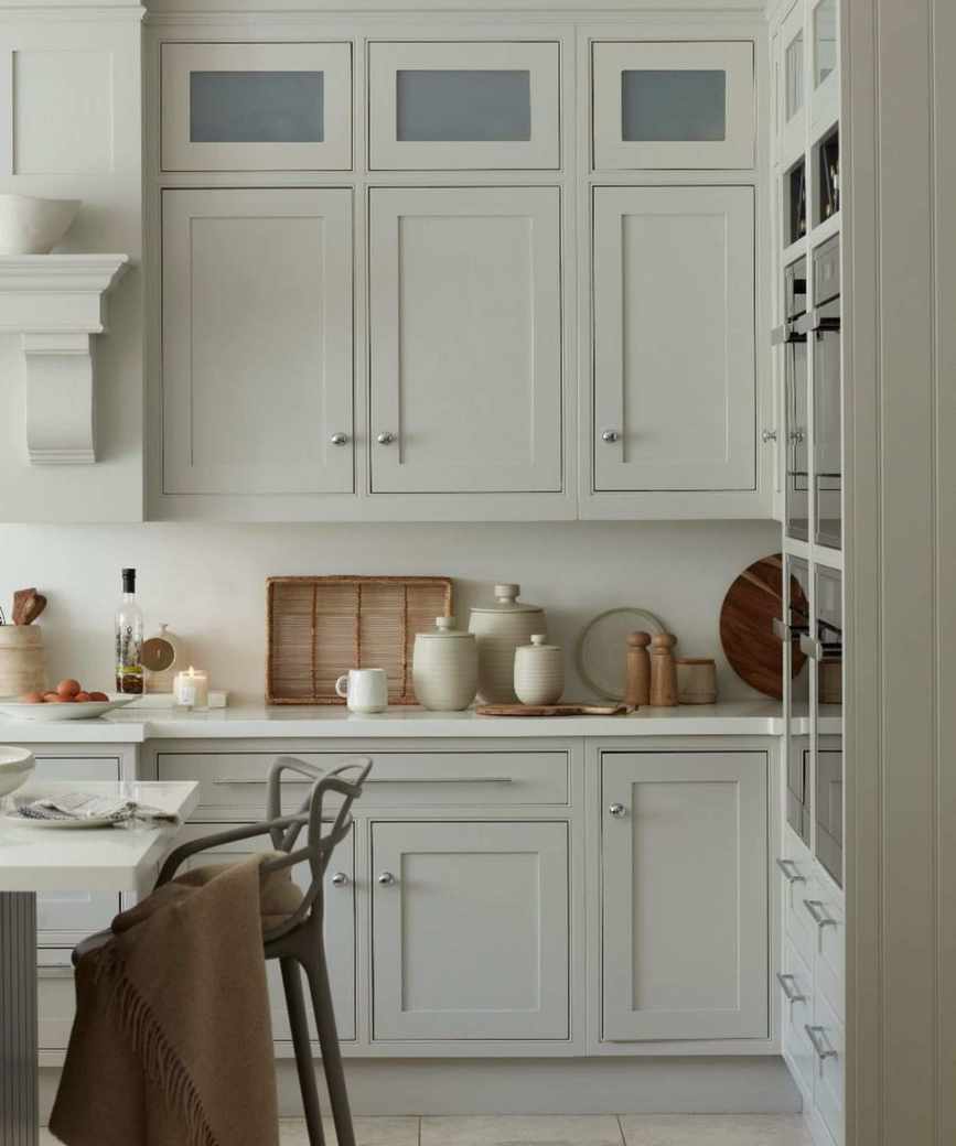 A white kitchen with styled countertops, chopping boards and baskets line the wall, with a woven wicker basket