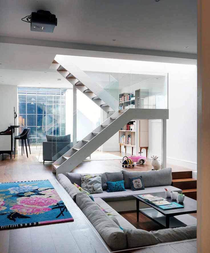 An open plan living room with sunken living area and black projector on the ceiling