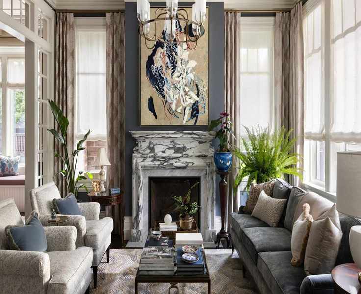 a traditional tudor-style living room with deep blue wall paint, lots of traditional windows, and a marble fireplace