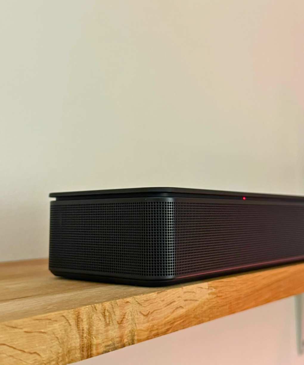 Corner of the Bose Smart Soundbar on a shelf in front of a white wall.