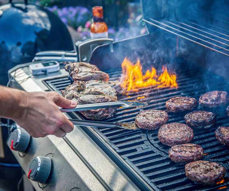 A gas grill with meat cooking on it
