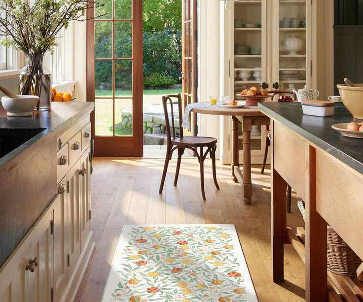 Bright and sunny galley kitchen with white and floral Ruggable runner in between cabinets on left and wooden island on the right
