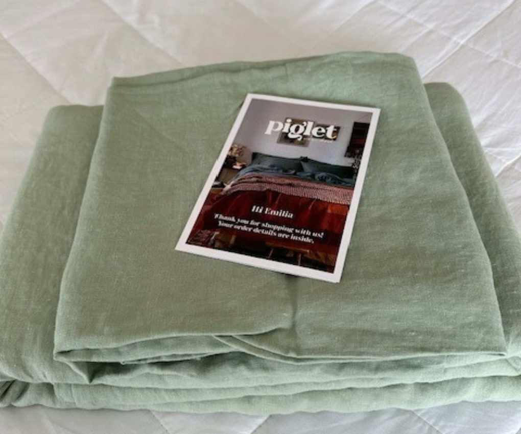 Piglet in Bed Sage Green Bedding Bundle folded on top of the mattress.