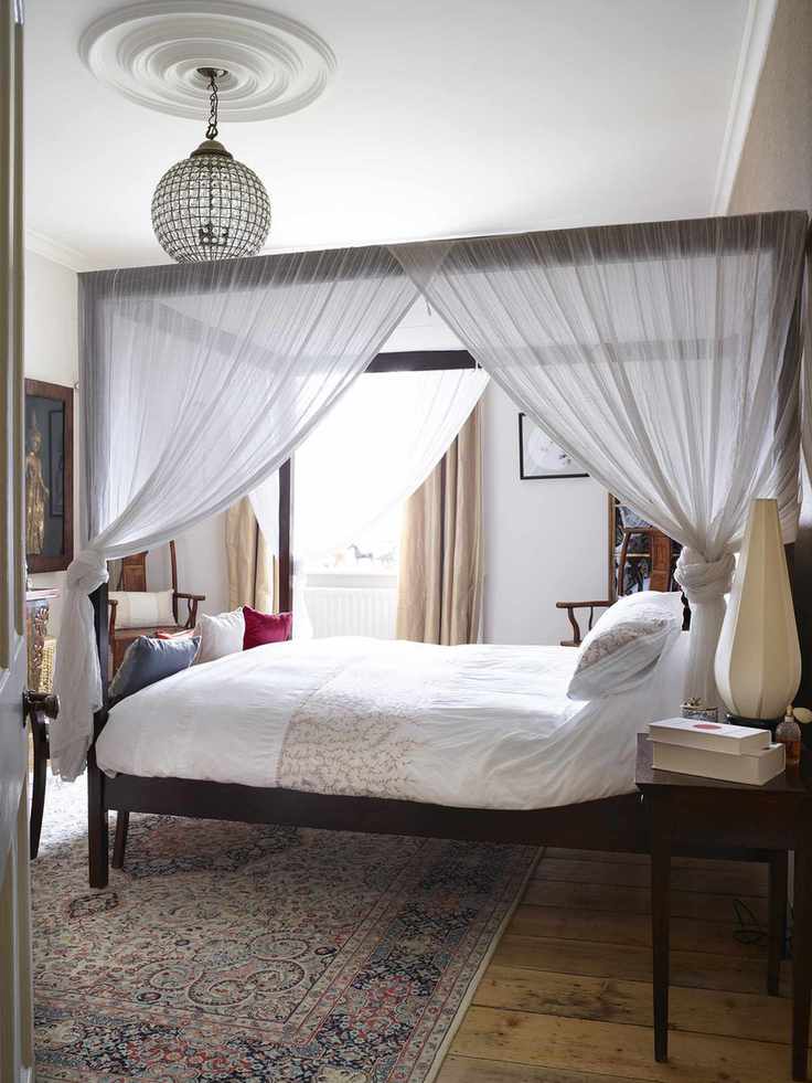 A guest room featuring a four-poster bed and a crystal chandelier in a Victorian home